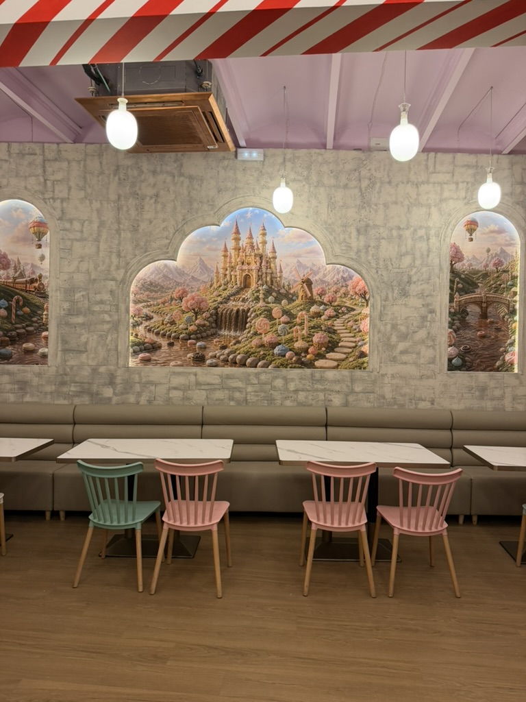 Comedor de Charlie Restaurante, con mural de castillo, mesas de mármol y sillas de colores