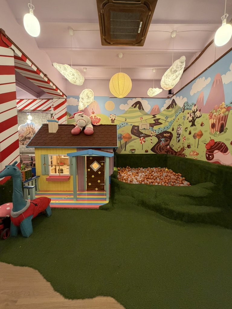 Casita de juegos de Charlie Restaurante, con peluche en el tejado, jirafa y piscina de bolas