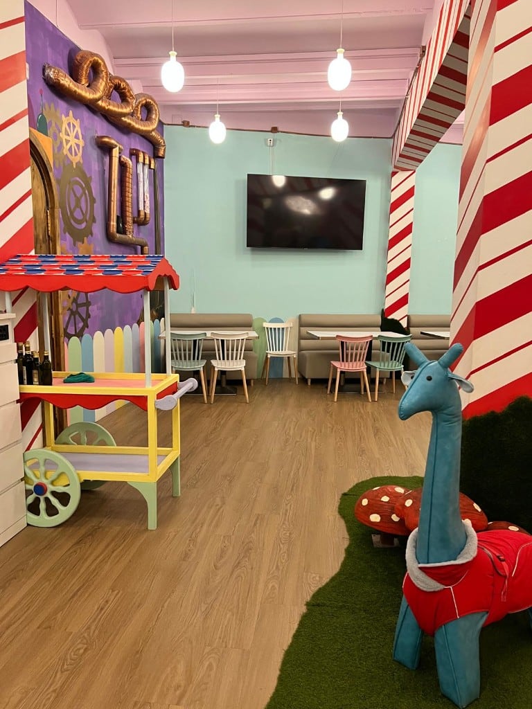 Interior of Charlie with candy-stripe columns, a toy cart and a plush giraffe