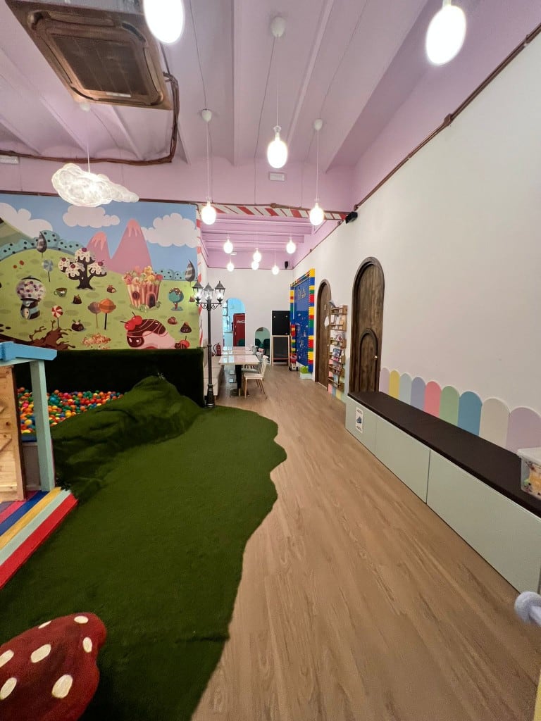 Play-area corridor at Charlie, with turf, a ball pit and a long bench